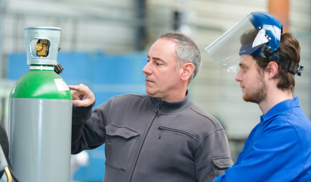 teacher showing student how to read welding gas bottle